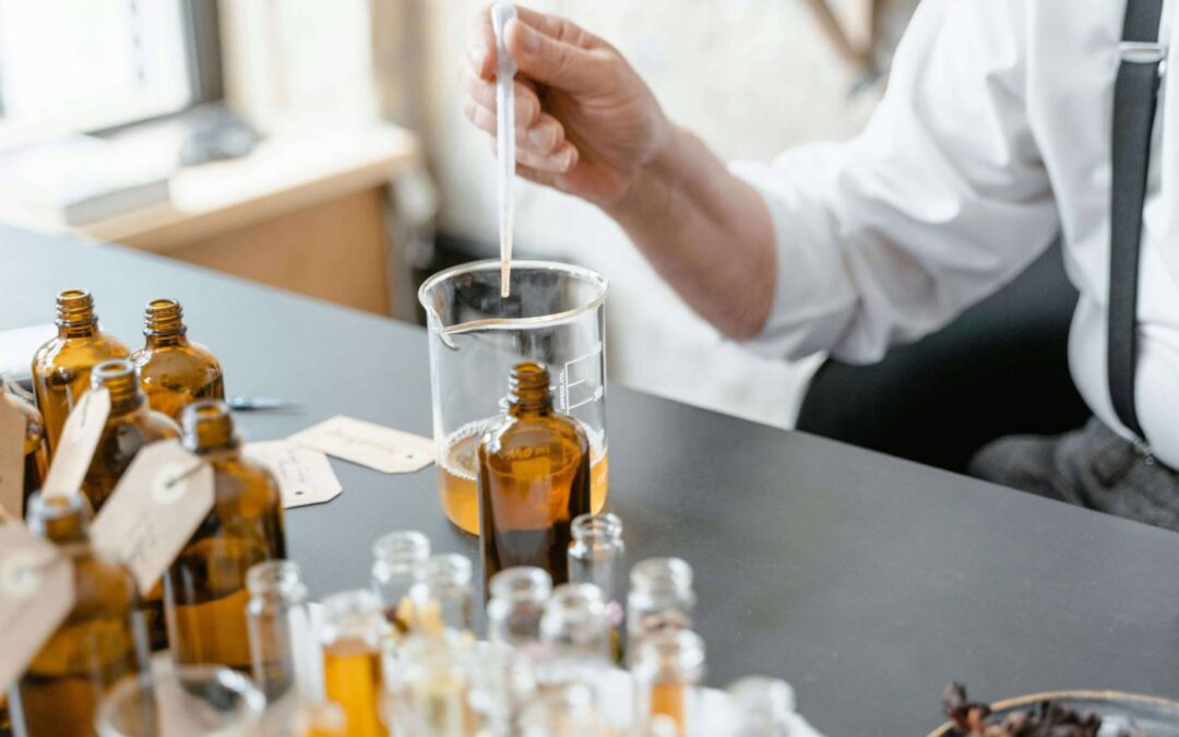 Person mixing essential oils in beaker.